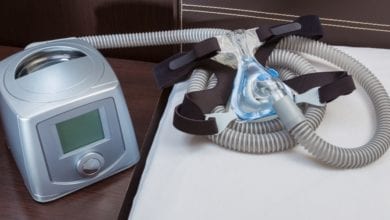 CPAP machine with air hose and head gear mask in a bedroom