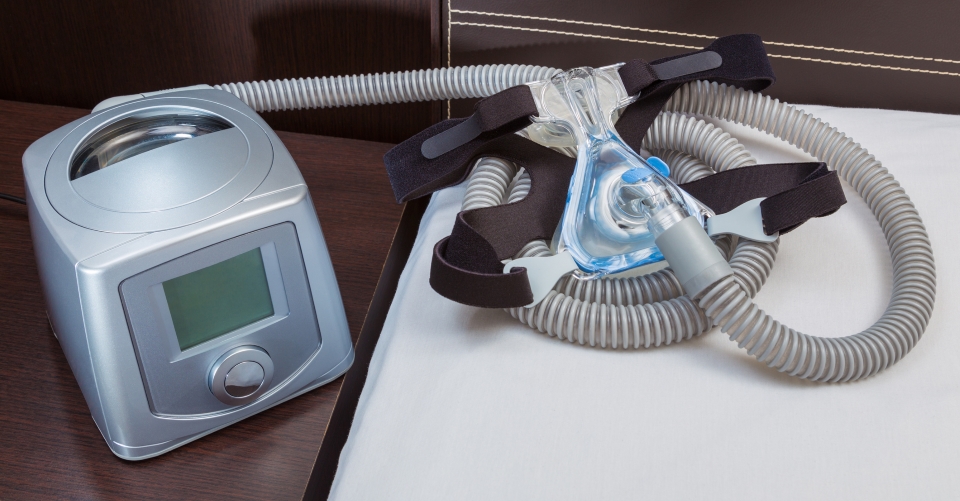 CPAP machine with air hose and head gear mask in a bedroom